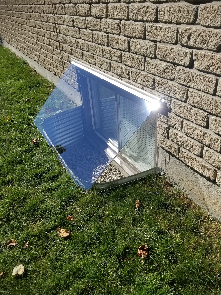 Clear sloped polycarbonate window well cover installed on a Canadian home